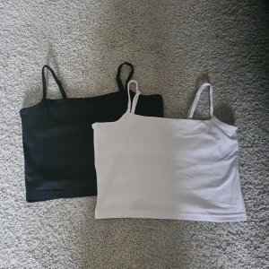 Svart och vit linnetopp 157 XS - Två stilrena linnetoppar från 157 i storlek XS, en svart och en vit. Båda har smala, justerbara axelband och är tillverkade i mjuk bomull med lite stretch för en skön passform. Perfekta att matcha med jeans eller kjol för en enkel och snygg look.
