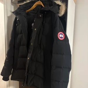 Svart dunjacka från Canada Goose - Säljer en svart dunjacka från Canada Goose i modell carson parka med klassisk patch på ärmen och stor huva med päls. Storleken är L men passar även M, jackan har används hyfsat mycket men inga defekter eller likande. Säljs pga den ej passar min stil längre. 