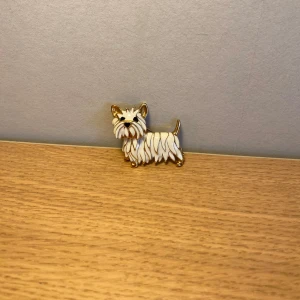 Brosch schnauzer - Supergullig brosch i form av en liten hund,terrier, en schnauzer hund. Broschen är guldfärgad med vit emalj. Har även lås, pinnen till låset i är lite silverfärgat. Den är ca 3 cm bred och ca 3 cm hög. Har inga stämplar. Hör av er vid frågor!💕
