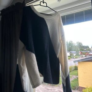 Svartvit stickad tröja med mönster - Säljer en stickad tröja med coolt svartvitt mönster i asymmetriska former. Tröjan har rund hals och långa ärmar, perfekt för dig som gillar en unik stil. Materialet är mjukt och skönt, passar till jeans eller kjol.