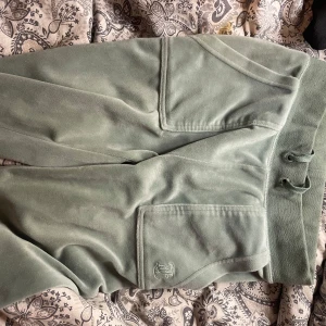 Gröna juicy couture byxor  - Snygga gröna mjukisbyxor med bred resår och snörning i midjan. Byxorna har stora fickor framtill och ett broderat ankare på ena fickan. Perfekta för chill eller häng med kompisar.
