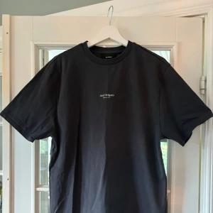 Svart t-shirt från Axel Arigato - Snygg svart t-shirt från Axel Arigato med minimalistiskt vitt tryck på bröstet. Klassisk rund halsringning och korta ärmar. Skön passform och tillverkad i mjuk bomull – perfekt till jeans eller shorts.