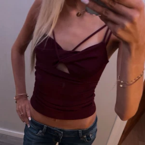 Vinrött linne - Säljer en vinröd croppad linnetopp från BikBok i storlek XS. Toppen har smala axelband, twistad detalj framtill och en liten cut-out under bysten. Snygg passform och stretchigt material som sitter tight. Perfekt för dig som gillar trendiga och stilrena plagg. Aldrig använd☺️