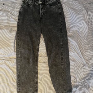 Svarta straight jeans Jack & Jones - Snygga svarta jeans från Jack & Jones med tvättad look. Modellen har raka ben och klassisk femficksdesign. Jeansen är tillverkade i kraftigt denimtyg och har normal passform. Perfekta för dig som gillar en stilren och avslappnad vibe. Storlek W 29 L 32