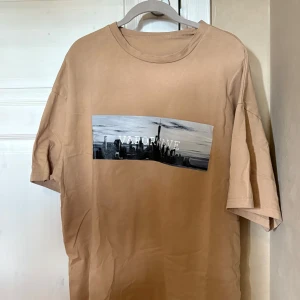 Beige oversized t-shirt  - Snygg beige oversized t-shirt från SHEIN i storlek L med ett tryck. Materialet är mjuk bomull som känns skönt mot huden.