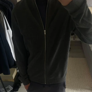 Mörkgrå kofta/tröja med dragkedja - Mörkgrå kofta med hel dragkedja framtill Långärmad och i mjukt material för extra komfort. inte alls använd mycket för att den har varit för stor för mig