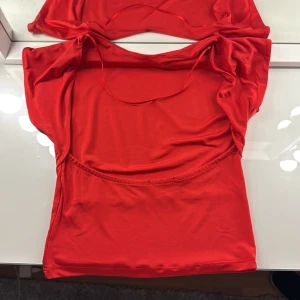 Röd topp med öppen rygg - Snygg röd ärmlös topp i ett mjukt och stretchigt material. Perfekt för en somrig look eller att bära under en kavaj. Toppen har en enkel design med rund halsringning. Aldrig använd💘