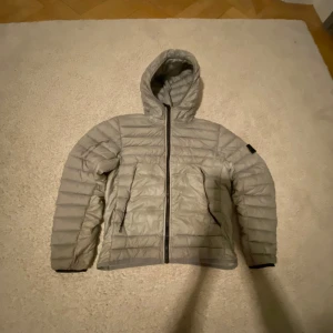 Grå/grön jacka från Stone Island Junior - Säljer en grå/grön jacka från Stone Island Junior. Säljer jackan för att den har blivit för liten storlek xs