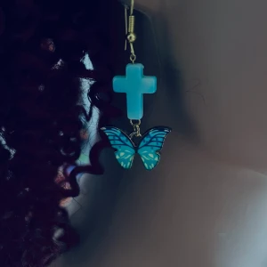 By prisförslag- 1 st Blå örhängen med kors och fjäril - Unikt örhängen med ett blått kors och en hängande fjäril i matchande blå nyanser. Perfekt för att lägga till en färgglad touch till din stil.