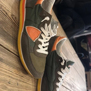 Gröna sneakers från Philippe Model - Snygga gröna sneakers från Philippe Model med vita snören och orange detaljer. Otroligt snygg färg kombination enligt mig, perfekt nu när det börjar bli vår! En riktigt STEAL, pris kan förhandlas 