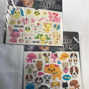 Tillfälliga tatueringar med djurmotiv - Två ark med tillfälliga tatueringar som har söta djurmotiv. Innehåller olika färgglada figurer som kaniner, hundar och andra fantasidjur. Perfekt för att dekorera huden med roliga och lekfulla mönster.