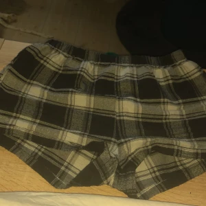 Rutig shorts från Shein - Säljer ett par bekväma och stiliga rutiga shorts från Shein. De är i svart och vitt med elastisk midja för extra komfort. Perfekta för en avslappnad dag.