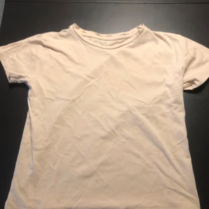 Beige t-shirt från 157 - Säljer en enkel och stilren beige t-shirt från 157 i 100% ekologisk bomull. Perfekt för en avslappnad look. T-shirten har korta ärmar och en klassisk rund halsringning.