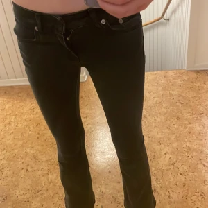 Svarta bootcut jeans från 157 - Snygga svarta bootcut jeans från 157 med låg midja. Perfekta för en stilren look. De har en klassisk design med dragkedja och knappar framtill.
