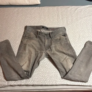 Grå jeans från Replay - Snygga grå jeans från Replay med en klassisk femficksdesign. De har en diskret broderad detalj på bakfickan och en stilren look. Perfekta för en avslappnad stil.