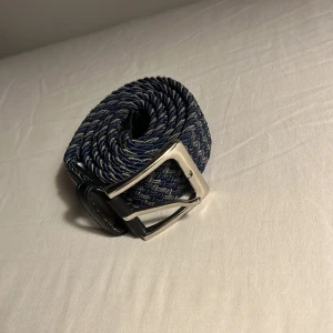 Grisch bälte 115 cm - Snyggt blått flätat bälte med ett stilrent silverfärgat spänne. Perfekt för att ge en extra touch till din outfit. Bältet har en unik textur och passar bra till både jeans. TAR EMOT ALLA PRISFÖRSLAG!