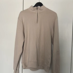 Beige tröja med dragkedja från Mywearman - Säljer en stilren beige tröja från Mywearman. Tröjan har en dragkedja vid halsen och långa ärmar. Perfekt för en avslappnad look.