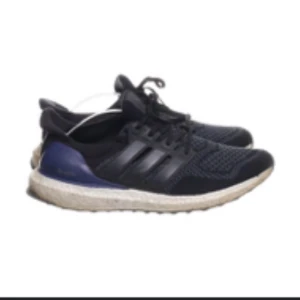 Svarta Adidas Ultraboost sneakers - Snygga svarta Adidas Ultraboost sneakers med en vit sula och blå detaljer. Skorna har en stickad ovandel och klassisk snörning för en bekväm passform.