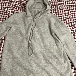 Grå hoodie - Säljer en mysig grå hoodie med dragsko i huvan. Perfekt för kyliga dagar med sin mjuka och bekväma passform. Den har ribbade muddar vid ärmslut och nederkant.