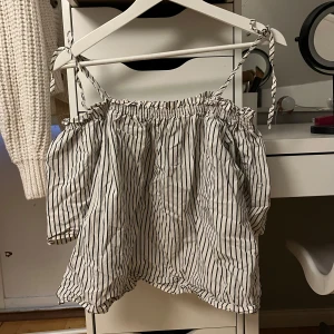 Randig offshoulder blus - Säljer en söt randig offshoulder blus med knytband vid axlarna. Perfekt för en avslappnad och stilren look. Blusen har en luftig passform och är gjord i ett lätt material.