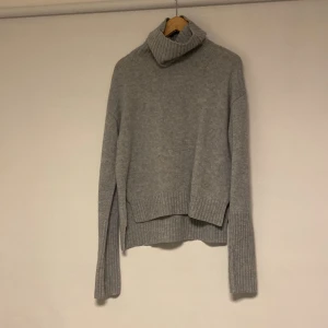 Grå polotröja från Filippa K - 100% ullSäljer en stilren grå polotröja från Filippa K. Tröjan är stickad och har långa ärmar med ribbade detaljer vid ärmslut och nederkant. Perfekt för kyliga dagar. 
