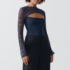 Mörkblå spetsdetaljerad topp - Elegant mörkblå topp med långa spetsärmar och en unik cut-out design framtill. Perfekt för en stilfull look. En slutsåld skit snygg tröja dock för stor för mig 