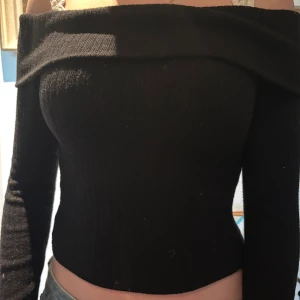 Svart offshoulder topp - Snygg svart offshoulder topp med lång ärm. Perfekt för en stilren look. Nestan ny.