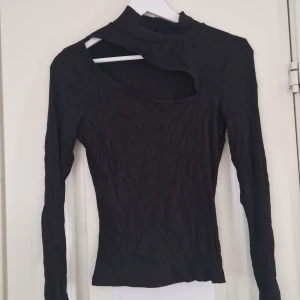 Svart långärmad topp  - Snygg svart topp med lång ärm och unik design Perfekt för en stilren look. Passar bra till både jeans och kjol.