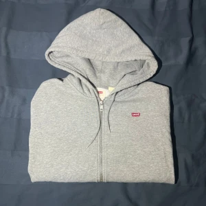 Grå hoodie från Levi's - Säljer en grå fin zip hoodie från Levis. Tröjan har inga hål eller defekter och är så gott som ny!✅ Vid snabb köp så fraktar jag samma dag!🚚😊 Storlek S men skulle säga att den passar M