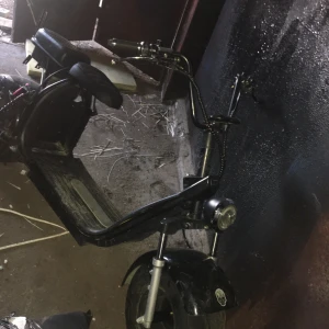 Fatbike trimmad går ca 100km/h ,, 6000w batheri - Ingen bok syns på bilden, endast en svart el-scooter eller moped i ett garage eller förråd. Ingen information om titel, författare eller innehåll kan utläsas.