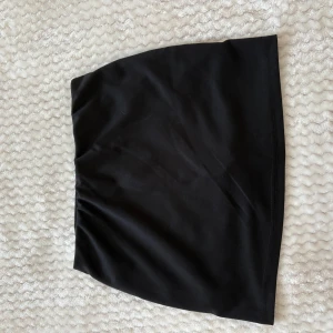 Svart enkel kortkjol - Säljer en svart, stilren och enkel kortkjol med rak passform. Kjolen är helsvart utan mönster eller detaljer och passar perfekt till en trendig vardagslook. Materialet känns mjukt och följsamt.