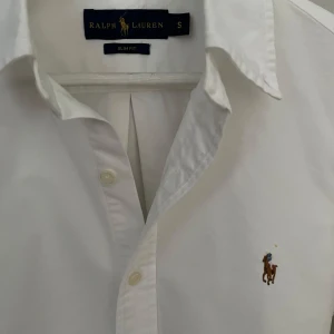 Vit Ralph Lauren Skjorta - Strl S, Slim Fit - Hej säljer nu min fina Ralph Lauren skjorta i storlek S och den sjukt populära modellen Slim Fit. Den är i nyskick och kommer vara otroligt snygg på sommaren. Nypris cirka 1600kr! Vid frågor eller fundering tveka inte på att höra av dig! 🌊🍾
