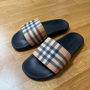 Burberry tofflor - Lite sönder men går att fixa med lim droppar. Syns inte när man har på sig. Annars använd lite. Storlek 44