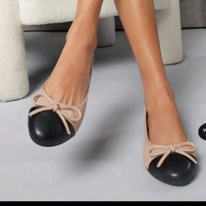 Beige ballerinaskor med svart tå och rosett - Snygga ballerinaskor i beige med svart rund tå och en söt rosett framtill. Skorna har en klassisk och stilren design som passar perfekt till både jeans och kjol. Tillverkade i ett slätt material som ger en elegant känsla. Endast testade, HELT NYA. 🤩Pris kan diskuteras. Vid köp av både dessa skor samt dem andra som ligger under min profil, får man båda för 150 kr. 🩷🩷🙌🏼