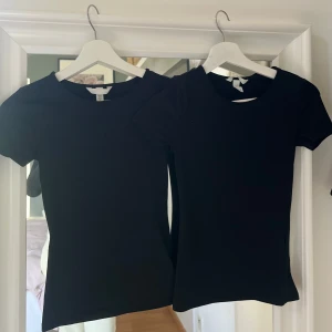 2 st svarta bas-t-shirts från H&M XS - Två svarta, klassiska t-shirts från H&M i storlek XS. Modellen är enkel med rund halsringning och korta ärmar. Perfekt till jeans eller kjol, och i mjuk bomull som känns skön mot huden. Snyggt basic-plagg som funkar året runt. Sitter tight på mig som har XS/S!
