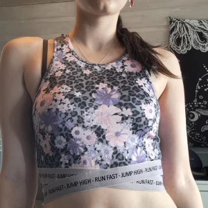 Blommig leopardmönstrad linnetopp - Sportig croppad linnetopp med grå leopardmönster och lila samt rosa blommor. Resårband nertill med texten RUN FAST - JUMP HIGH. Väldigt bekvämt och skönt att träna i men faller inte riktigt mig i smaken. Plagget är i storlek S :)