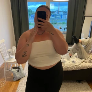 Vit bandeau tubtopp - Säljer en enkel och fräsch vit bandeau tubtopp. Toppen är croppad och axelbandslös, perfekt för varma dagar eller när du vill ha en clean look. Sitter tight och är lätt att matcha med både jeans och kjol.