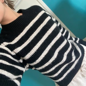 Randig svartvit stickad tröja - Säljer en stickad tröja med breda svarta och vita ränder. Tröjan har lång ärm, ribbad mudd vid hals, ärmslut och nederkant. Perfekt för dig som gillar klassisk stil med en twist. Supermjuk och skön att ha på sig.
