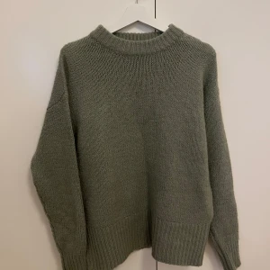 Grön stickad  tröja - Mysig grön stickad tröja med oversized passform och bred ribbad kant vid hals, ärmslut och nederkant. Perfekt för lager-på-lager och chill dagar. Enkel och stilren design som funkar till allt.