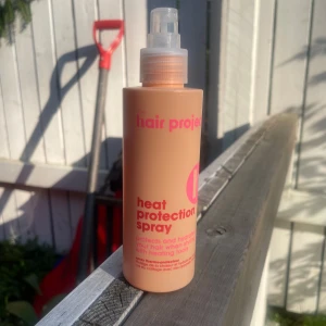 Heat Protection Spray från The Hair Project - 3/4 left.———smells kinda vanilla///////////////////////Peachfärgad värmeskyddsspray från The Hair Project med rosa text. Innehåller aloe vera, provitamin B5 och ricinolja som skyddar och återfuktar håret vid styling med värmeverktyg. Praktisk sprayflaska i plast, enkel att använda för att hålla håret fräscht och starkt.