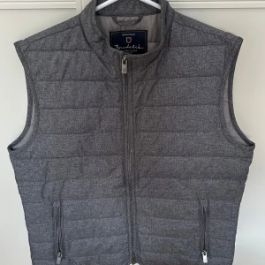 Grå quiltad dunväst från Bondelid - Snygg grå dunväst från Bondelid i klassisk quiltad design. Västen har hög krage, två fickor med dragkedja och hel dragkedja framtill. Perfekt för lager-på-lager och stilren look. 