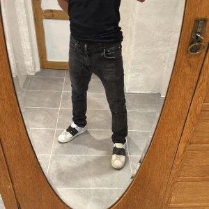 Svarta jeans från Nudie Jeans - Säljer ett par svarta jeans från Nudie Jeans med klassisk femficksdesign och diskreta slitningar. Jeansen har rak passform och normal midja, tillverkade i mjukt bomullstyg med snygg tvättad look. Perfekta för dig som gillar en stilren och avslappnad vibe.