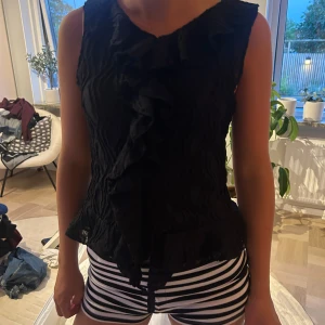 Svart volangblus med struktur - Säljer en svart blus/top från Gina, med struktur och volang🤗