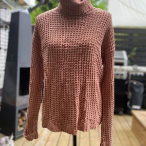 Brun stickad polotröja från NA-KD - Brunfärgad tröja med hög krage och långa ärmar. Tröjan har en stickad textur. Längd: 65cm, bystvidd: 60cm ﻿Uppvikta ärmslut ﻿100% akryl  Inga bilder när den sitter på mig! Katter finns i hemmet! Kan ej skicka med UPS!