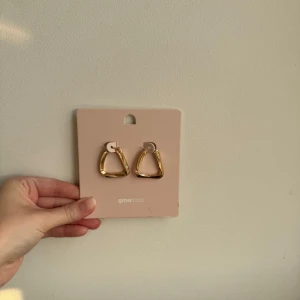 Guldiga örhängen från Gina Tricot - Helt nya örhängen från Gina Tricot, aldrig använda eller testade. Dessa är slutsålda och är en doop på de trendiga bottega veneta twisted hoop earrings✨ Perfekta för att ge din look en trendig touch. Lätta att matcha med olika outfits och riktigt statement utan att bli för mycket.
