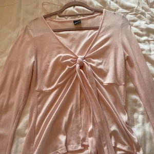 Ljusrosa topp  från Gina Tricot - Supersöt ljusrosa topp från Gina Tricot med lång ärm och knyt framtill. Toppen har v-ringning och är i ett mjukt, stretchigt material.  Använt några gånger, anars bra skick.🌸