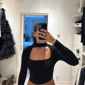 Svart croppad polotopp med cut out - Trendig svart croppad polotopp med lång ärm och stor fyrkantig cut out! Storlek M men passar även S