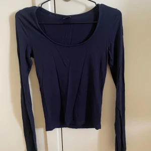 Mörkblå långärmad topp med slits - En stilren mörkblå långärmad topp med rund halsringning och slitsdetalj vid ärmslut. 
