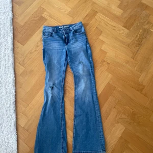 Blå bootcut jeans från Blue Ridge - Säljer ett par blå bootcut jeans från Blue Ridge med slitningar på benen och låg midja . 