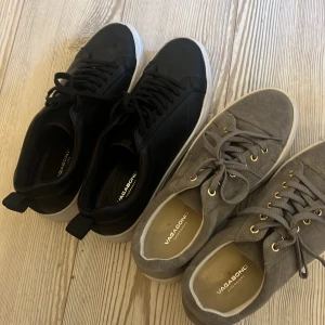 Vagabond sneakers i svart och grå mocka - Två par Vagabond sneakers med chunky vit sula. Ena paret är i svart skinn med svarta snören, det andra i grå mocka med grå snören och guldiga öljetter. Båda har rund tå och klassisk låg profil. Säljer pga för små, nypris 1200st båda kan man få för 1200